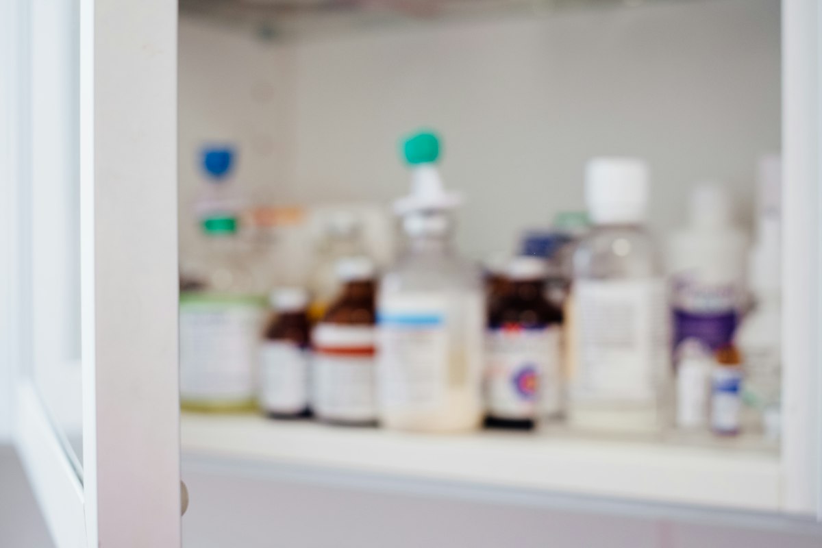 Pharmacist working in modern pharmacy with organized medicine shelves